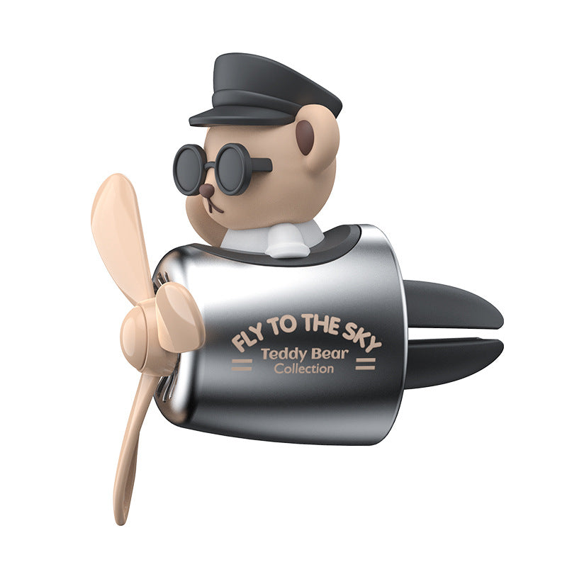 A teddy bear in a pilot outfit with a cute car air freshener, wearing sunglasses, on a white background.