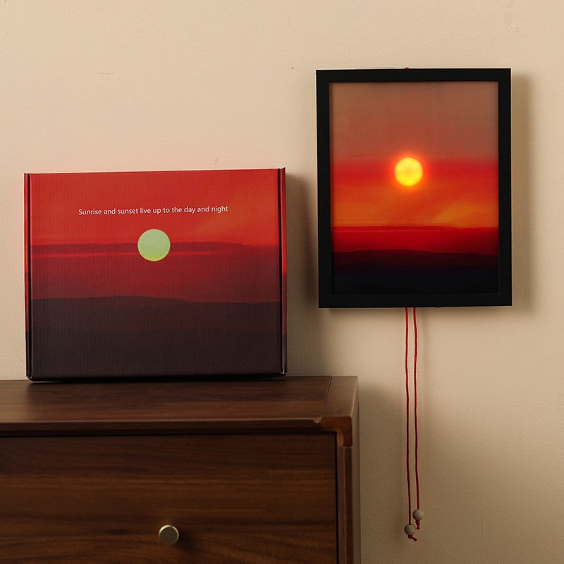Framed artwork of a sunset on a wall next to a matching box.