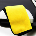Yellow microfiber towel draped over a car mirror with a black border.