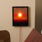 Framed artwork of a sunset wall light on a beige wall