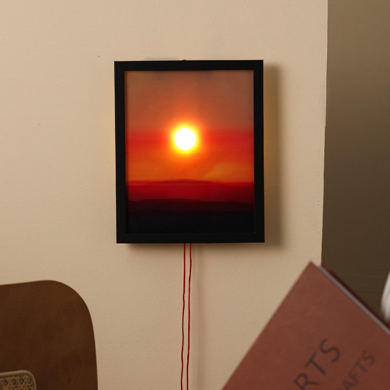 Framed artwork of a sunset wall light on a beige wall